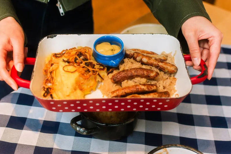 Deftiger Grünkohl mit Wurst und Kartoffeln auf einem Teller.