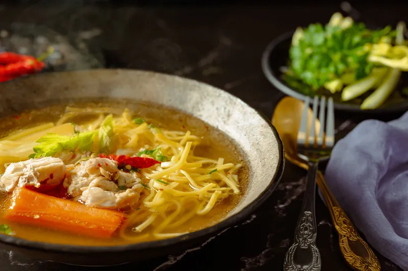 Eine Schüssel mit dampfender Hühnersuppe nach klassischem Rezept.