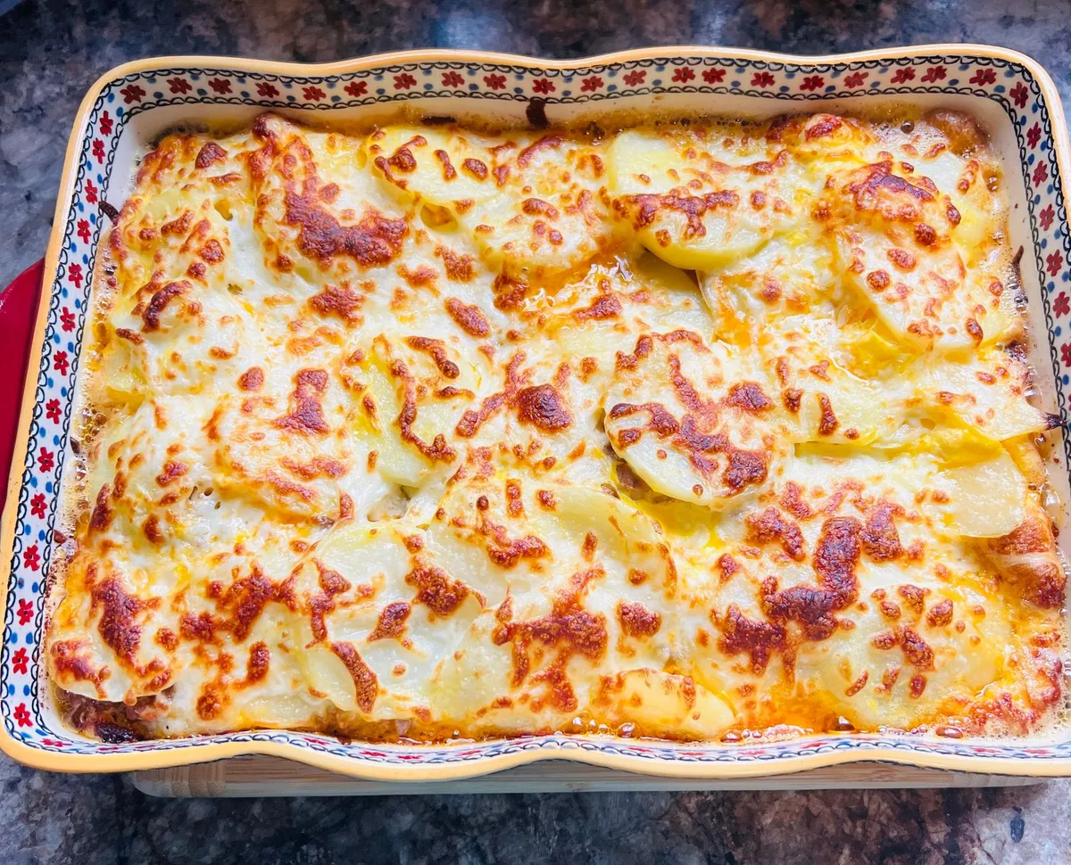Überbackener Kartoffelauflauf mit goldbraun geschmolzenem Käse in einer verzierten rechteckigen Auflaufform