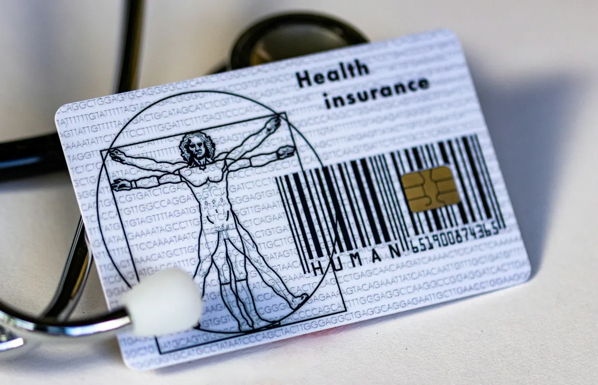 Gesundheitskarte mit Chip und Barcode, daneben liegt ein Stethoskop auf hellem Untergrund.