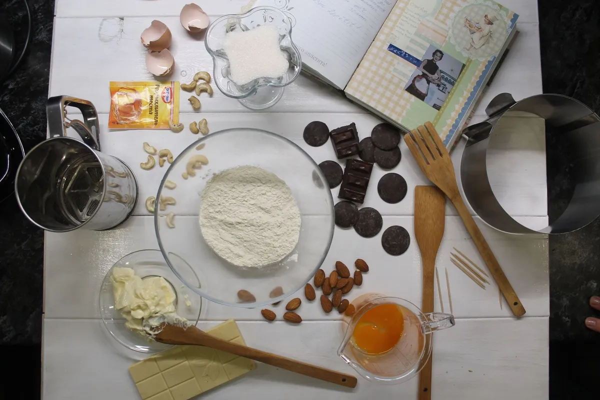 Zutaten für Nussecken wie Mehl, Butter und Haselnüsse auf Holz