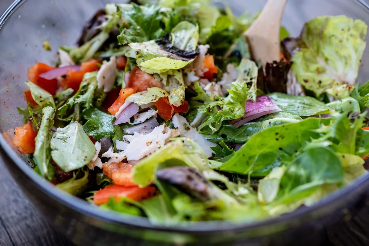 Eine große Schüssel mit gemischtem Salat aus verschiedenen grünen Blättern.