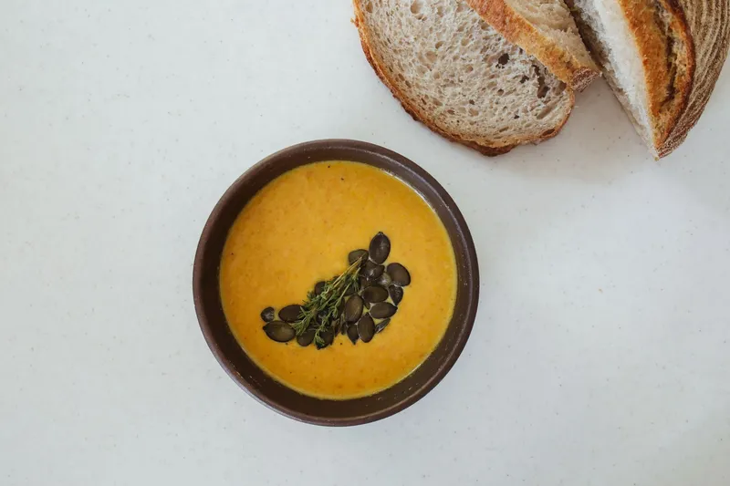 Cremige Kürbissuppe in einer Schale, garniert mit Kürbiskernen.